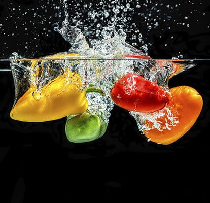 Des fruits colorés tombent dans l'eau
