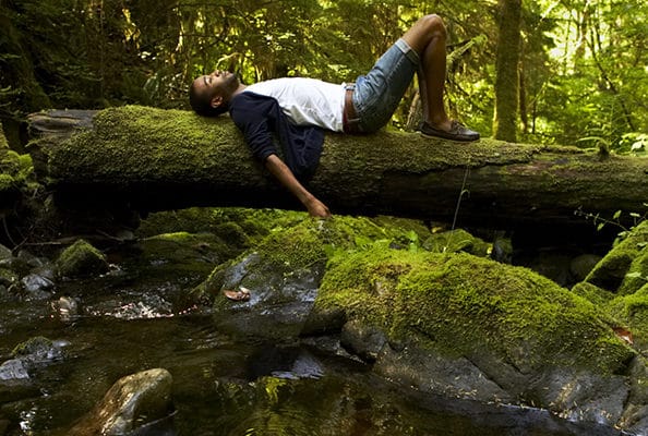 Un homme allongé sur un arbre dans une forêt