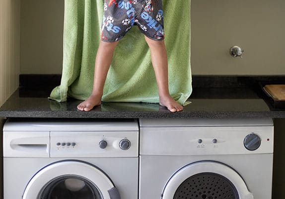 Un enfant joue à Superman sur un lave-linge